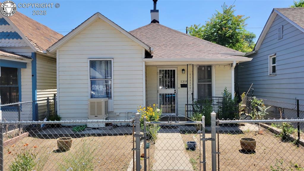 Caption: View of front of property with a gate, a fenced front yard, roof with shingles, covered porch, and a