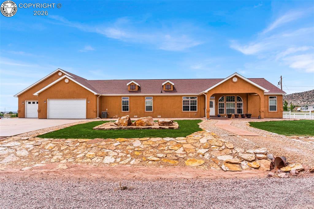 Caption: Stucco exterior with a covered entry, multiple dormer windows, and an attached three-car garage