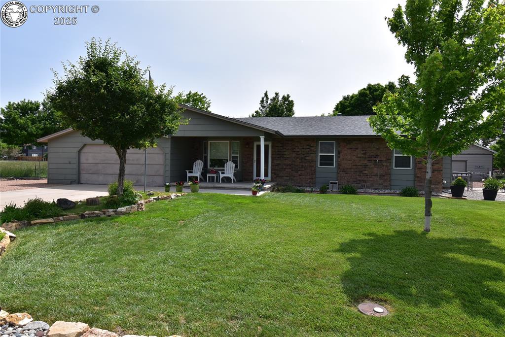 Caption: Ranch-style home featuring covered porch, a garage, a front lawn, concrete driveway, and brick sidin