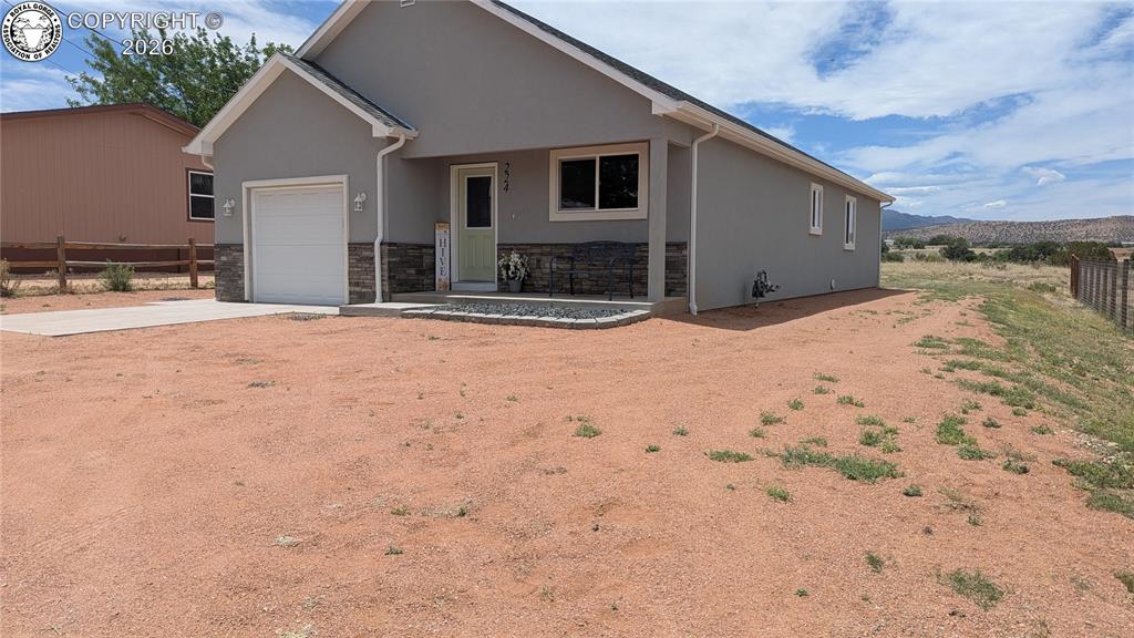 Caption: Contemporary ranch-style exterior with gray stucco siding and a stone veneer accent