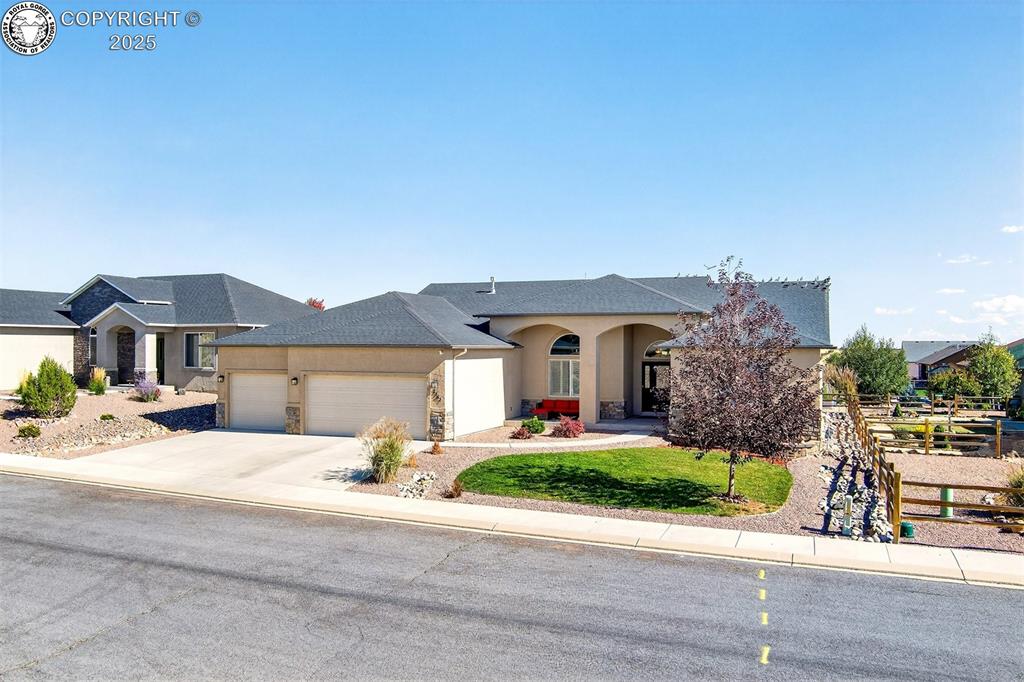 Caption: View of front of property with stucco siding, stone siding, concrete driveway, and an attached garag