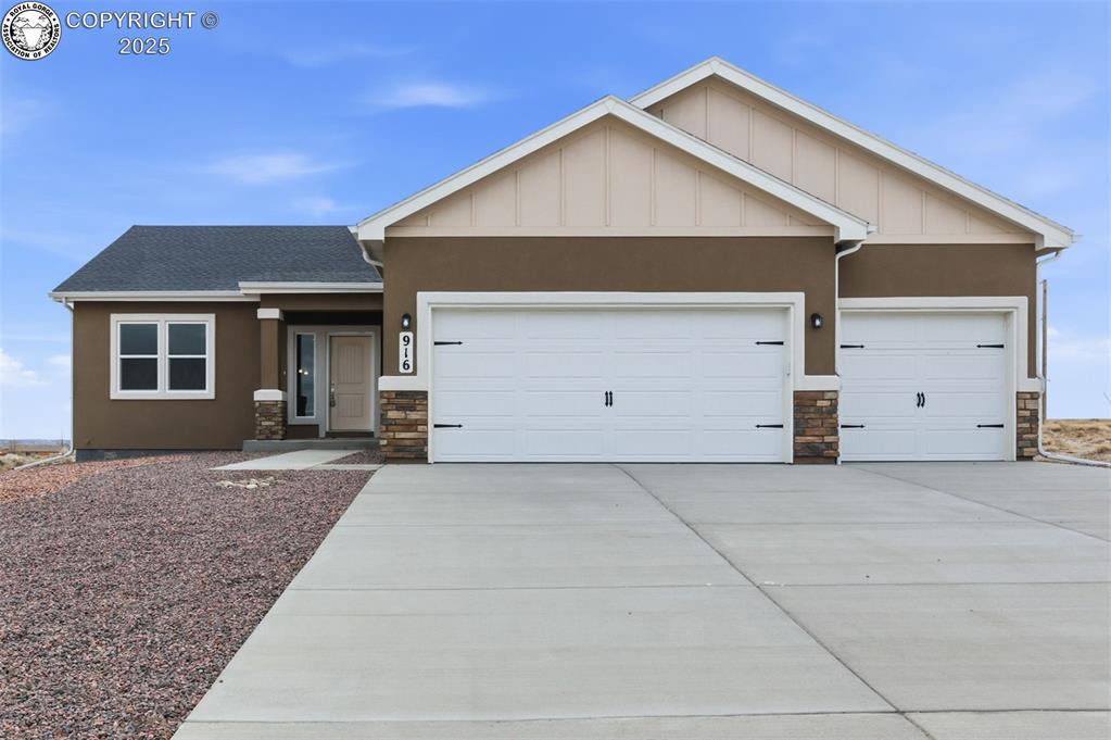Caption: View of front of property with stone siding, driveway, an attached garage, and roof with shingles