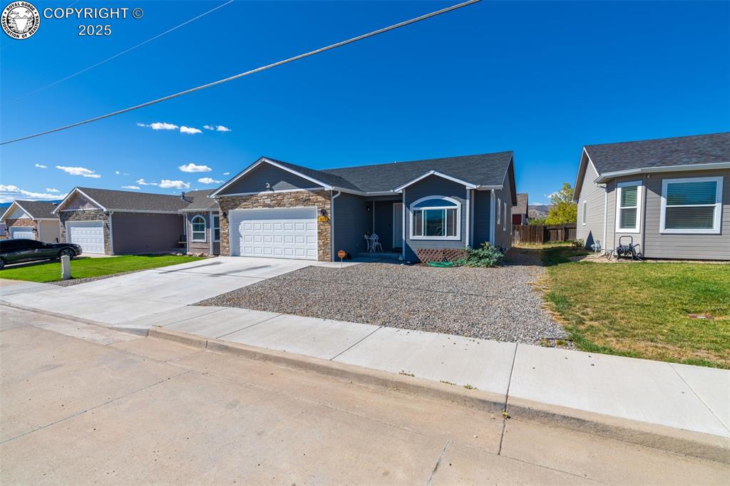 Caption: Ranch-style home with concrete driveway, stone siding, and an attached garage