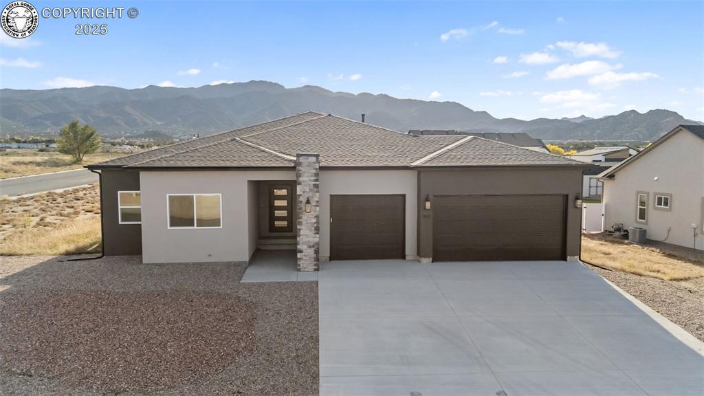 Caption: View of front of house with roof with shingles, a mountain view, a garage, stucco siding, and drivew