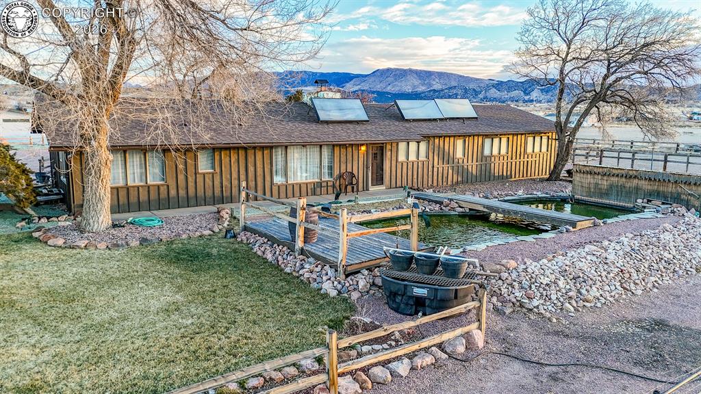 Caption: Back of property featuring board and batten siding, a mountain view, solar panels, a patio area, and