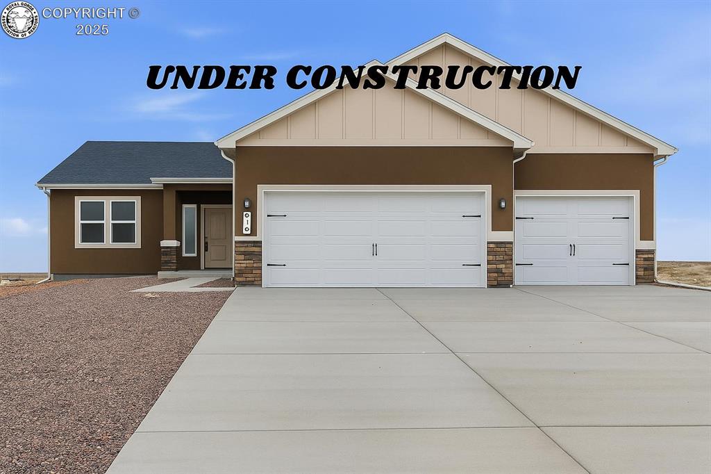 Caption: View of front of home featuring stone siding, driveway, a garage, and stucco siding