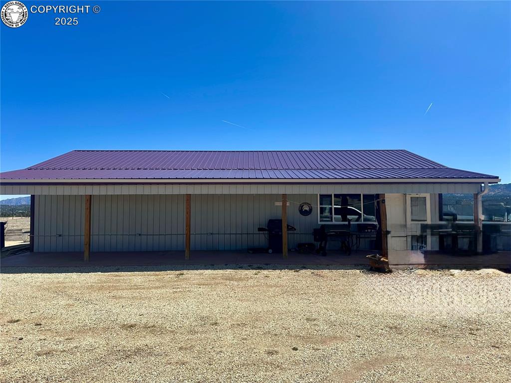 Caption: View of front facade with a metal roof and a carport