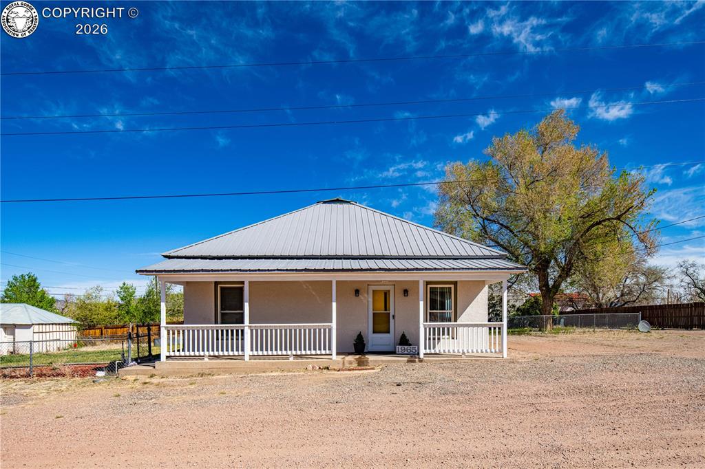 Caption: Farmhouse inspired home with a porch, a metal roof, and stucco siding