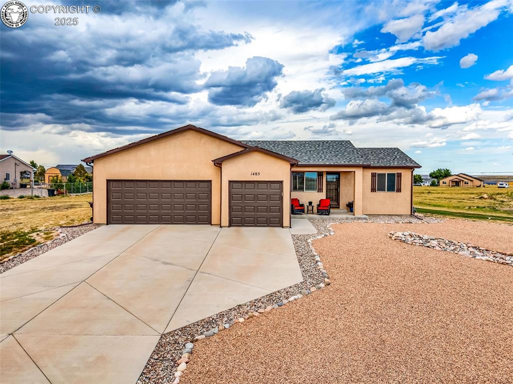 Caption: Ranch-style house with an attached garage, stucco siding, and driveway