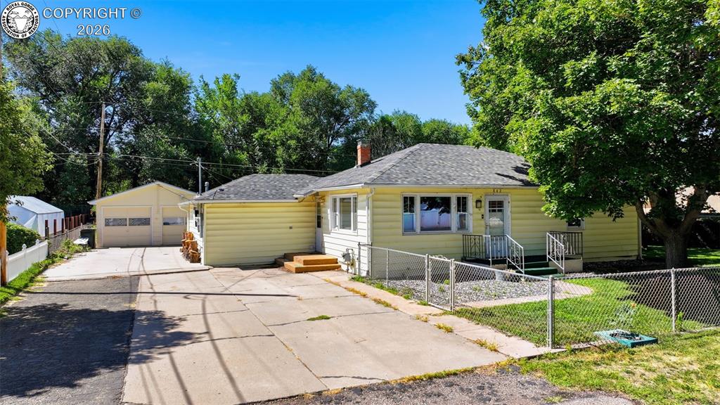 Caption: Exterior featuring yellow siding, a peaked asphalt shingle roof, and a two-car detached garage