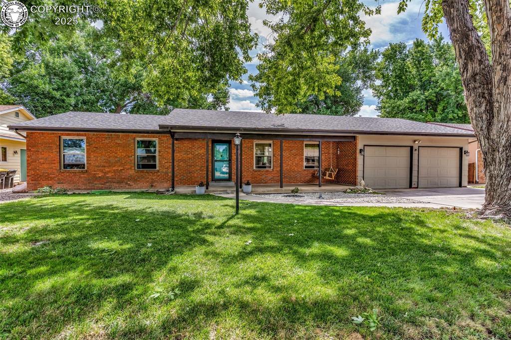 Caption: Ranch-style home with brick siding, an attached garage, and a front lawn