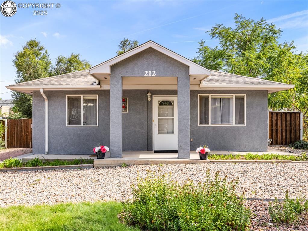 Caption: Bungalow-style house featuring stucco siding and a porch