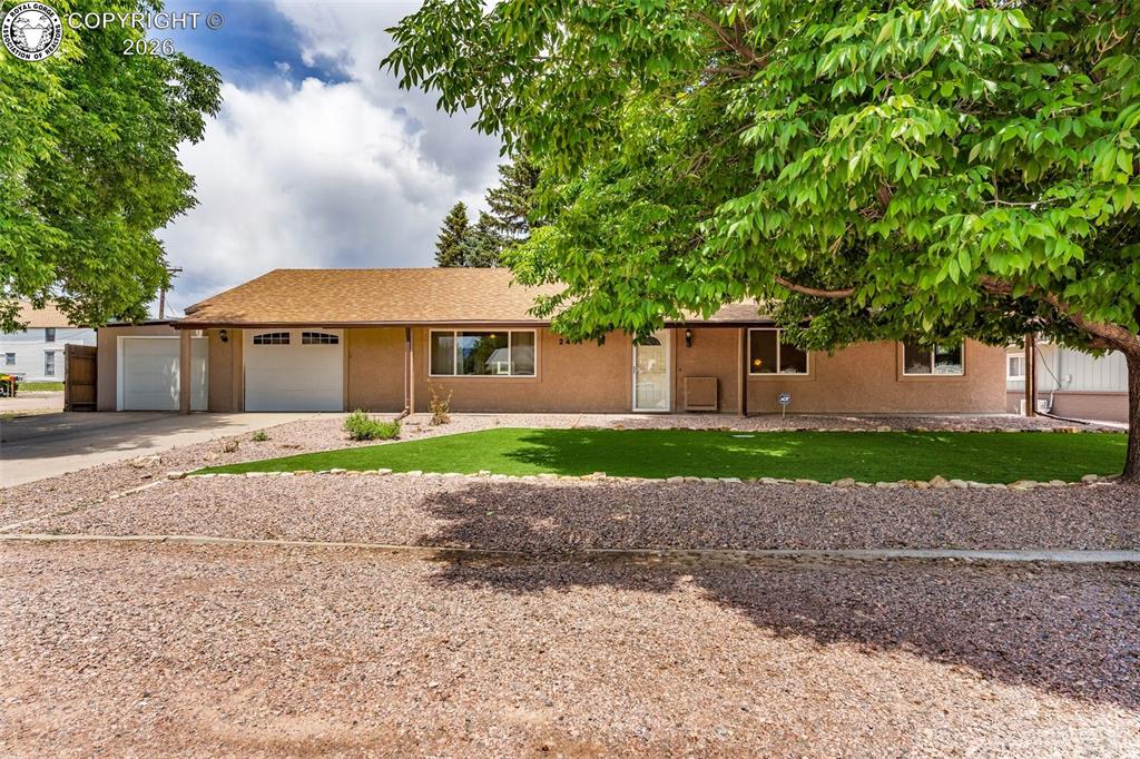 Caption: Ranch-style house featuring concrete driveway, an attached garage, a front yard, and stucco siding