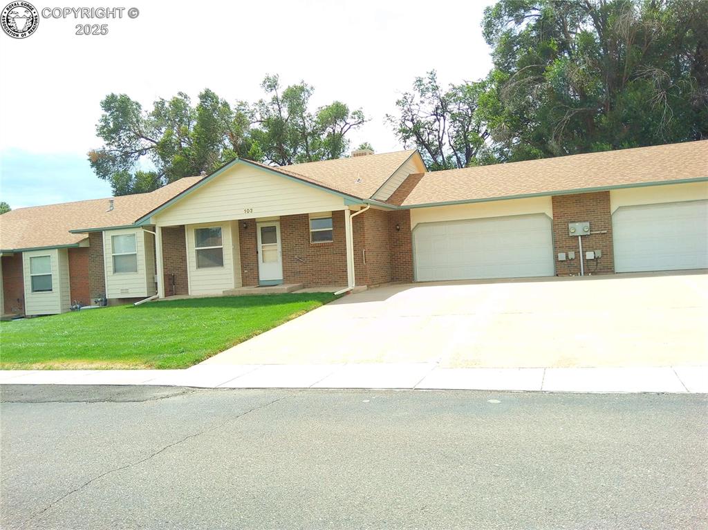 Caption: Single story home with driveway, a front lawn, brick siding, an attached garage, and covered porch