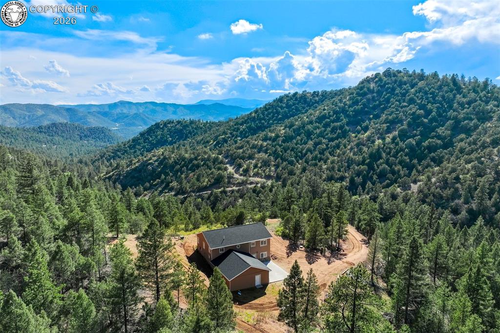 Caption: Mountainous landscape surrounding a two-story residence with a detached structure