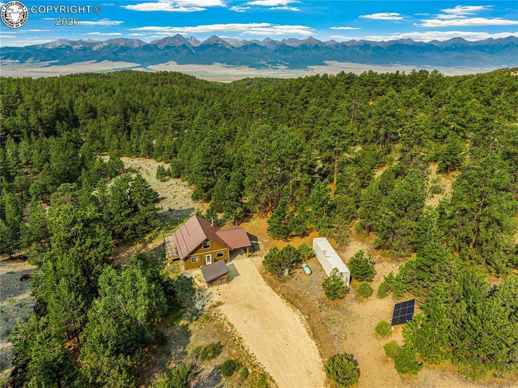 Caption: Mountain backdrop with a forested landscape surrounding a residence featuring a brown metal roof, li