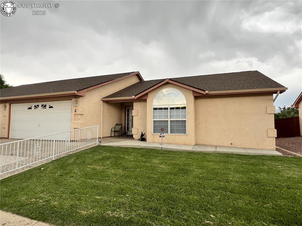 Caption: Single story home featuring a shingled roof, stucco siding, a garage, and driveway