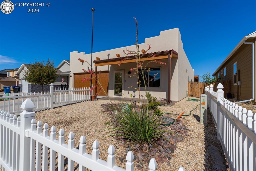 Caption: Stucco exterior with a wood-finish garage door and covered entry