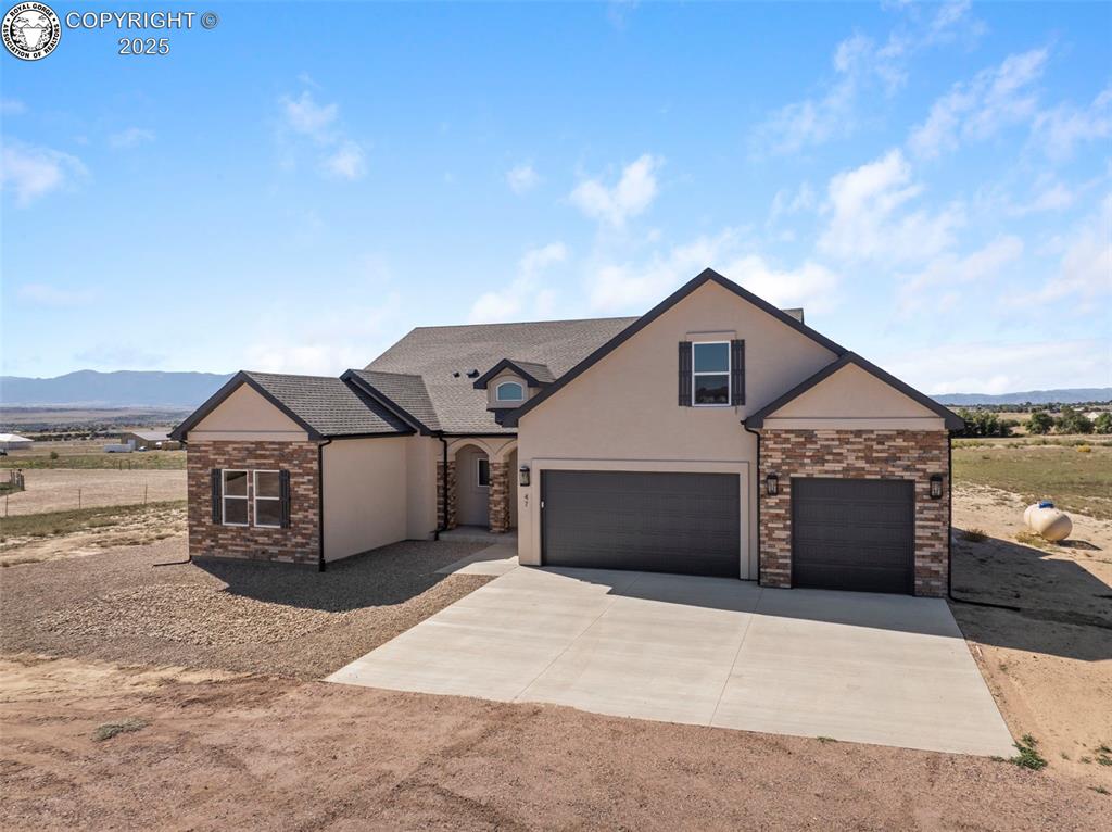Caption: View of front of home featuring concrete driveway, a mountain view, stone siding, and stucco siding