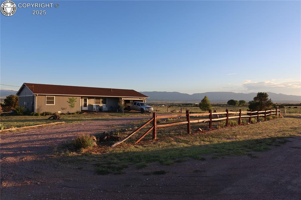 Caption: View of front facade with dirt driveway, a mountain view, and a view of countryside
