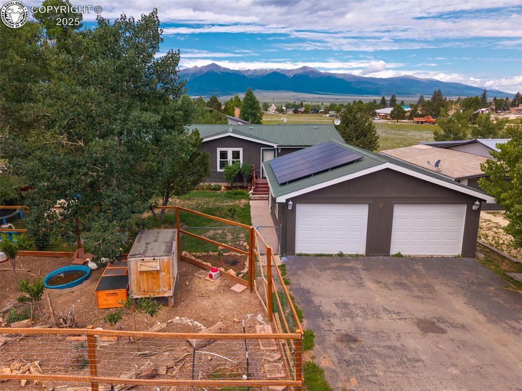 Caption: View of front of house featuring a mountain view, roof mounted solar panels, driveway, a metal roof,