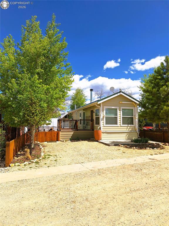 Caption: Single-story residence featuring light-colored siding, a covered deck, and a stone patio area
