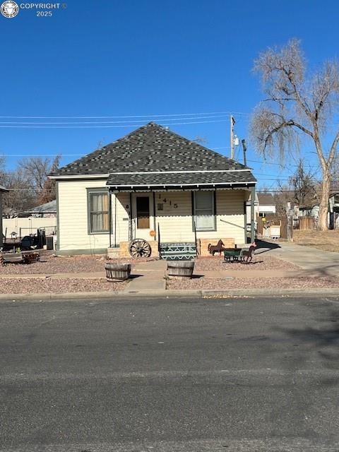 Caption: View of front of house featuring roof with shingles and covered porch