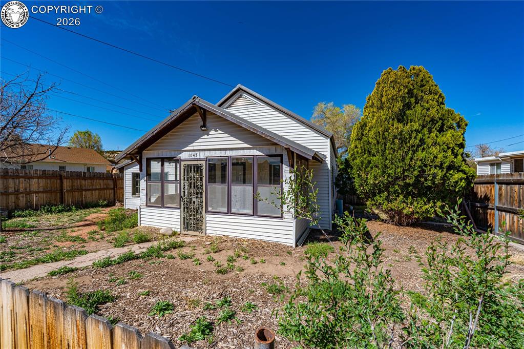 Caption: Rear view of property with a fenced backyard and a sunroom