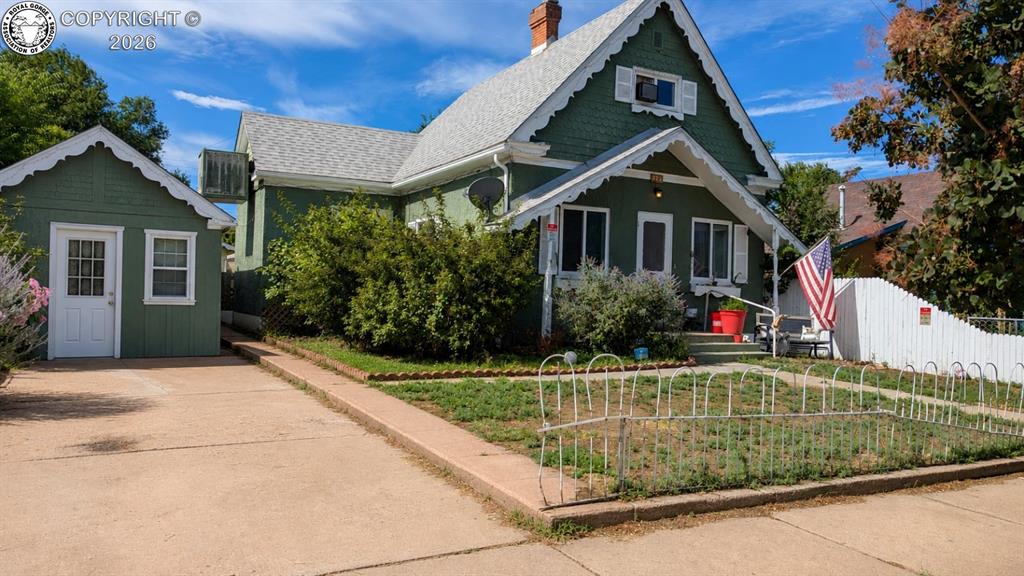 Caption: Green exterior with decorative white trim and a covered front porch