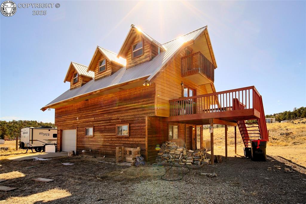 Caption: View of side of home with stairs to Main Level, a wooden deck, an attached garage, and metal roof.