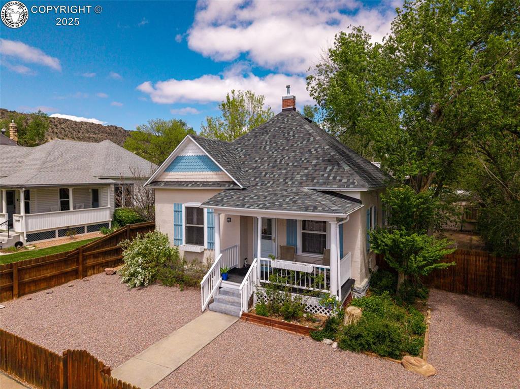 Caption: View of front facade featuring covered porch, a shingled roof, a chimney, and stucco siding