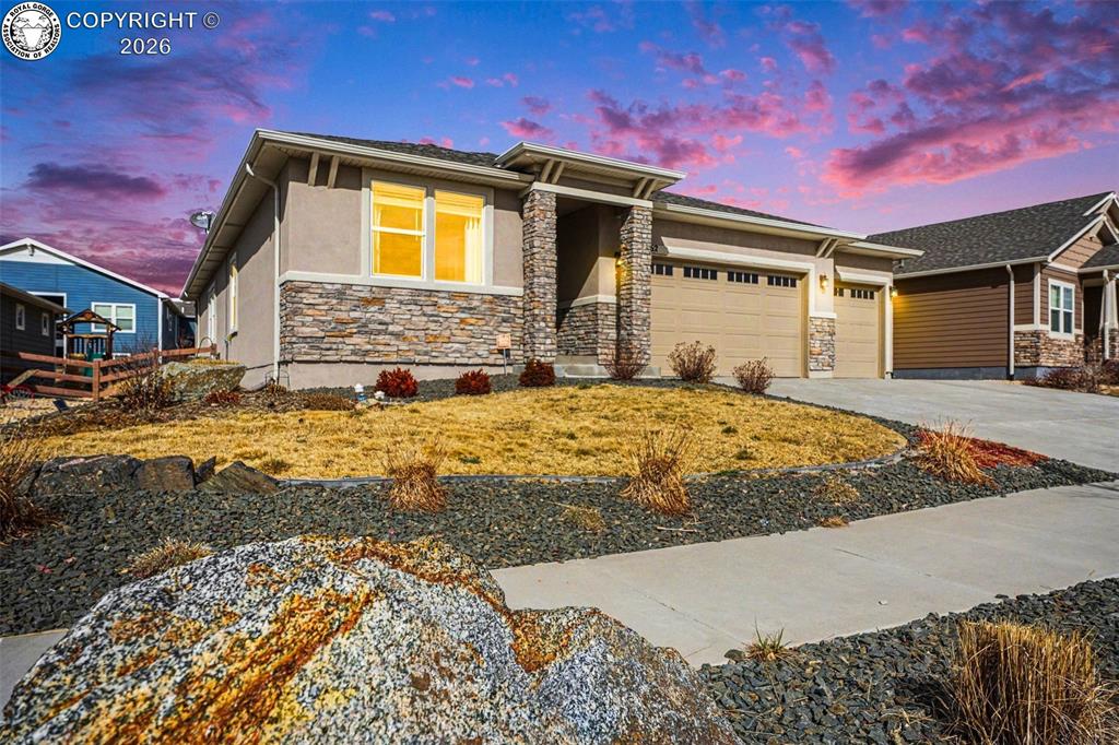 Caption: The home’s front exudes charm with a stucco exterior, a welcoming front patio, and a landscaped yard