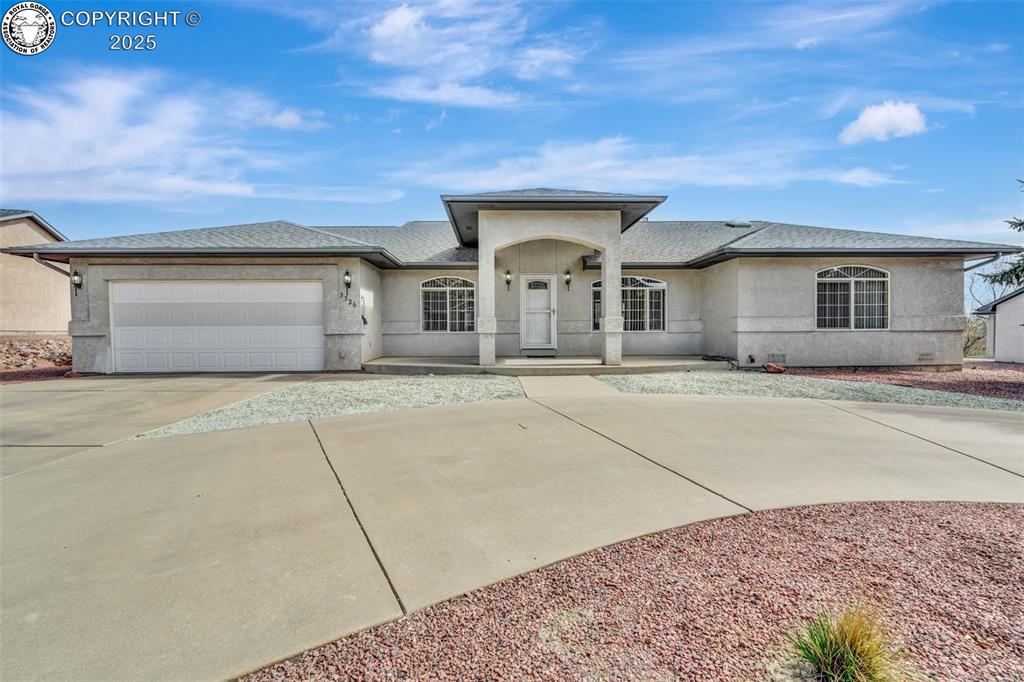 Caption: Prairie-style house with a shingled roof, driveway, stucco siding, and a garage