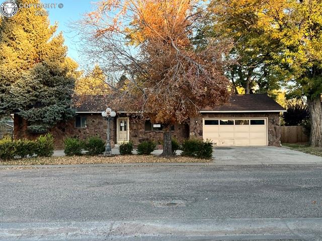 Caption: View of front facade with stone siding, concrete driveway, and an attached garage