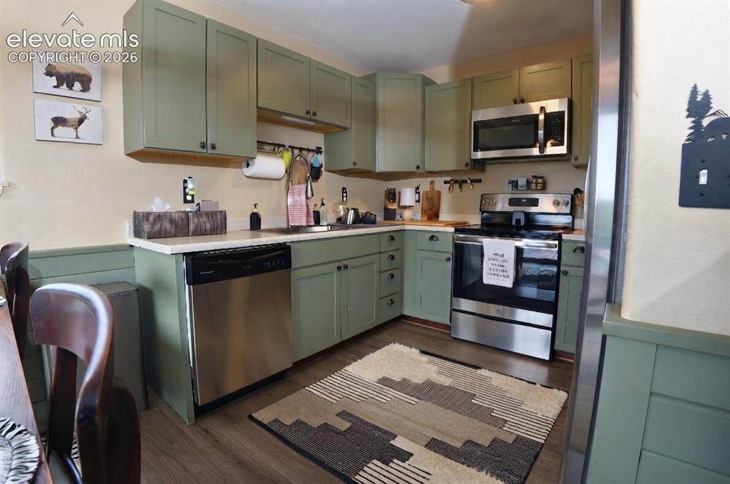 Image 14 of 46: Kitchen featuring green cabinetry, stainless steel appliances, wood-finish 