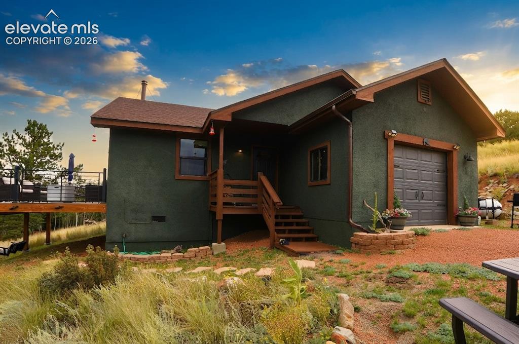 Image 32 of 46: Stucco exterior with wood trim accents, attached garage with panel door, ra