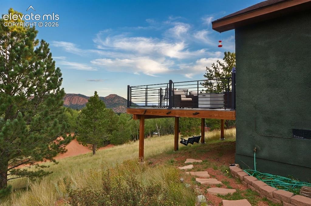 Image 6 of 46: Elevated wood deck with horizontal metal railings, a stucco exterior, and a