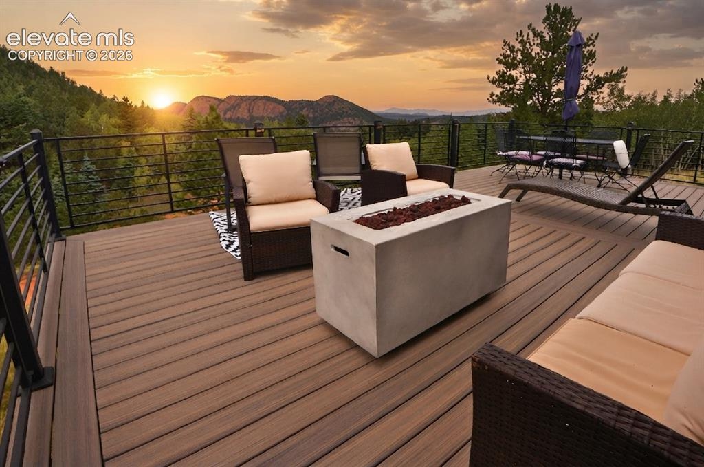 Image 8 of 46: Expansive outdoor deck featuring wood-finish decking, a concrete fire pit, 