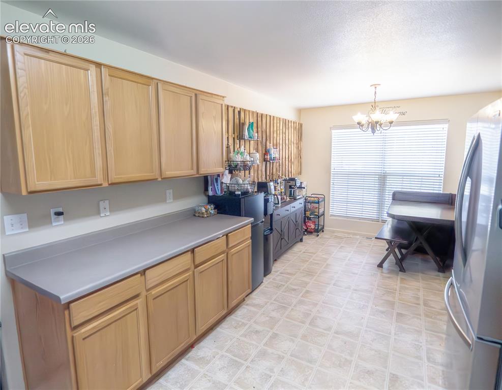 Image 4 of 13: Kitchen featuring light wood-finish cabinetry, grey countertops, and tile f