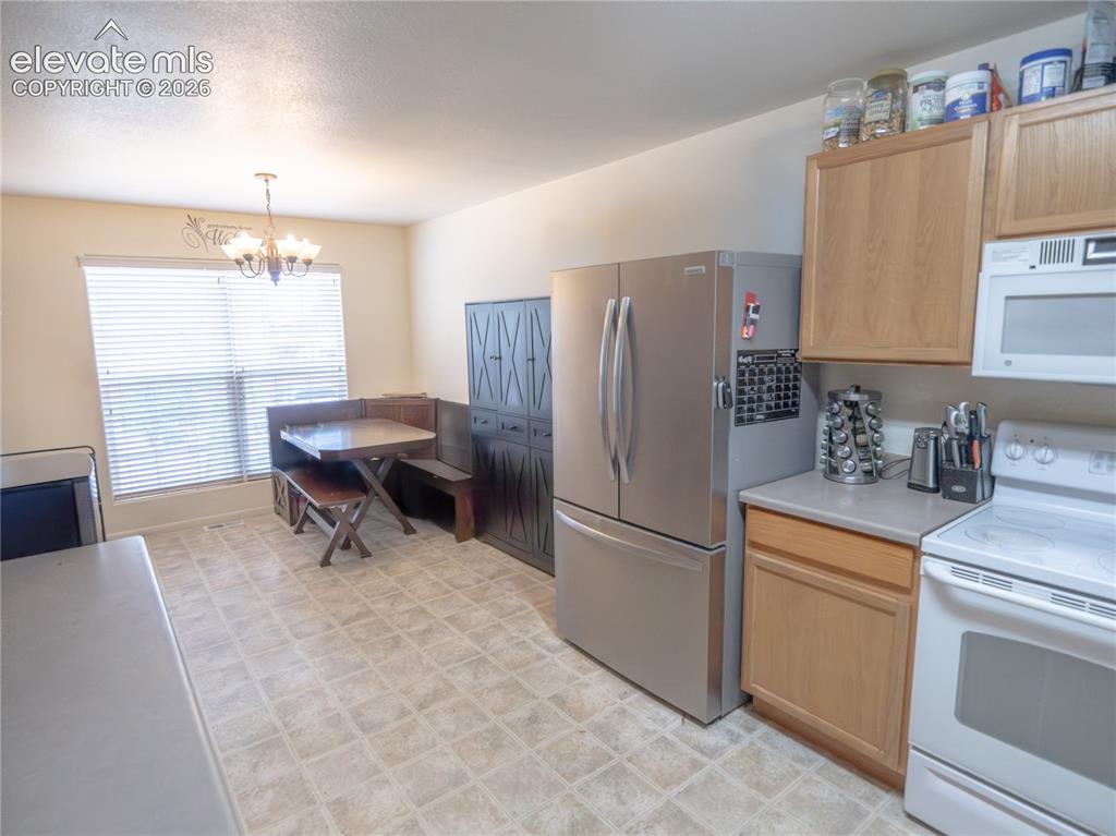 Image 5 of 13: Eat-in kitchen featuring light wood cabinetry, light-toned countertop, and