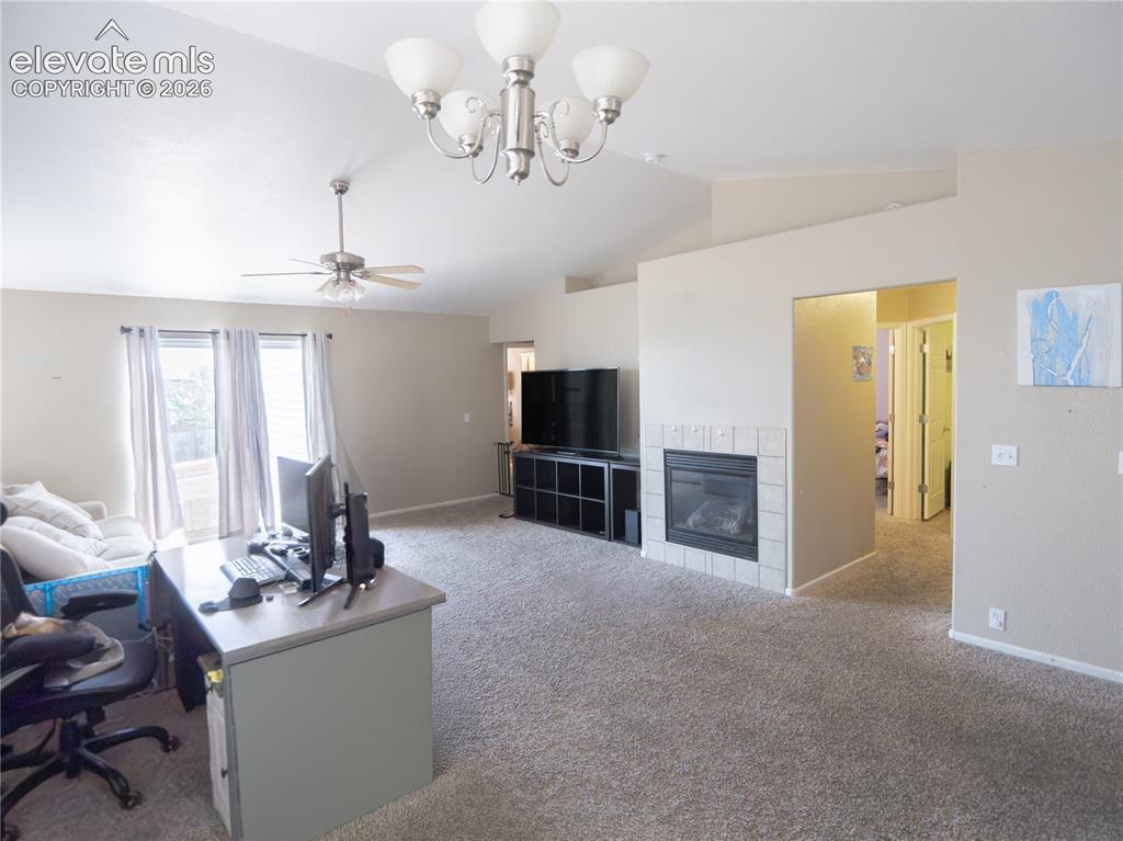 Image 7 of 13: Spacious room featuring vaulted ceilings, a ceiling fan, and a chandelier