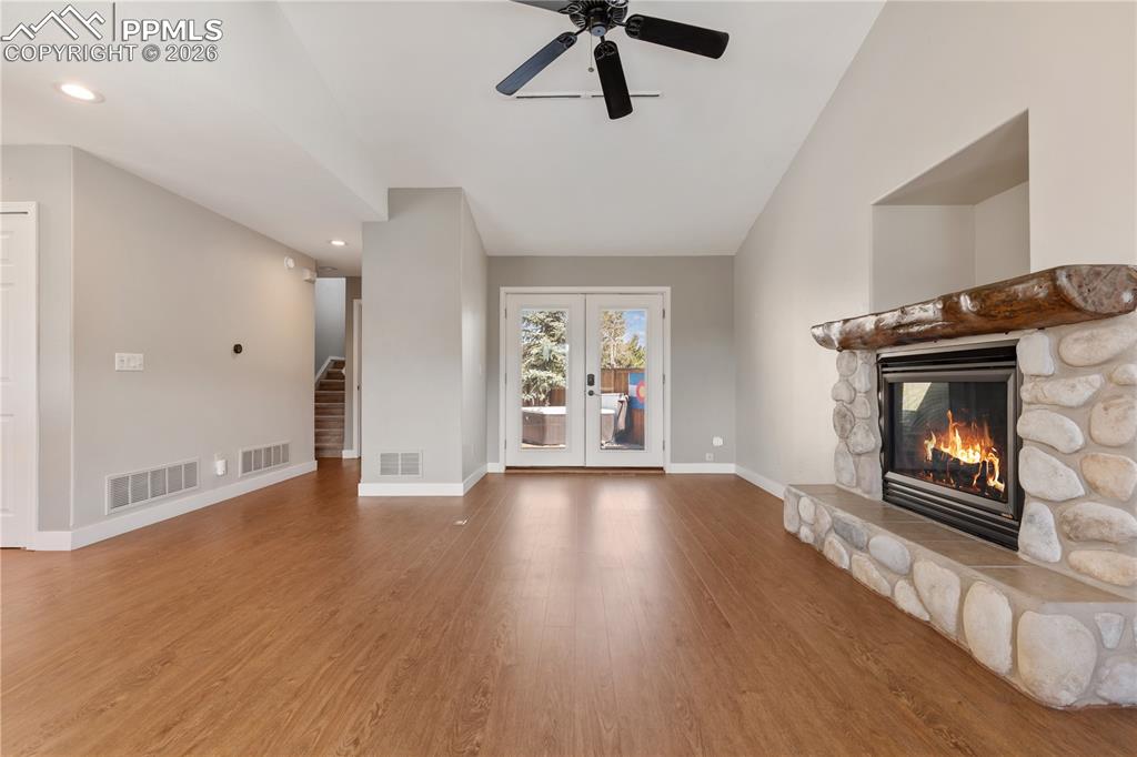 Image 10 of 29: Spacious living area featuring wood-finish flooring, a stone-surround firep