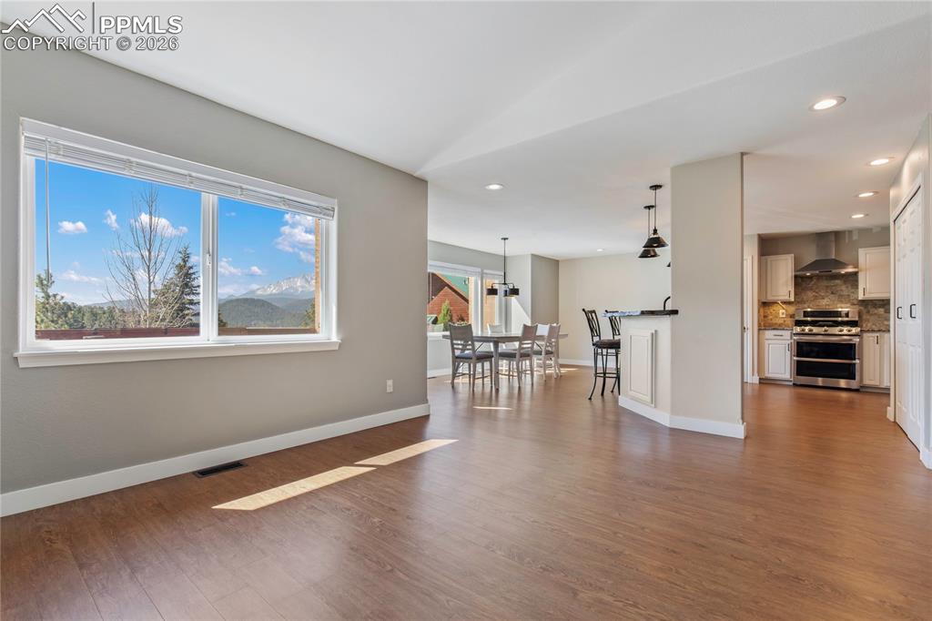 Image 13 of 29: Spacious living area featuring wood-finish flooring, a large picture window