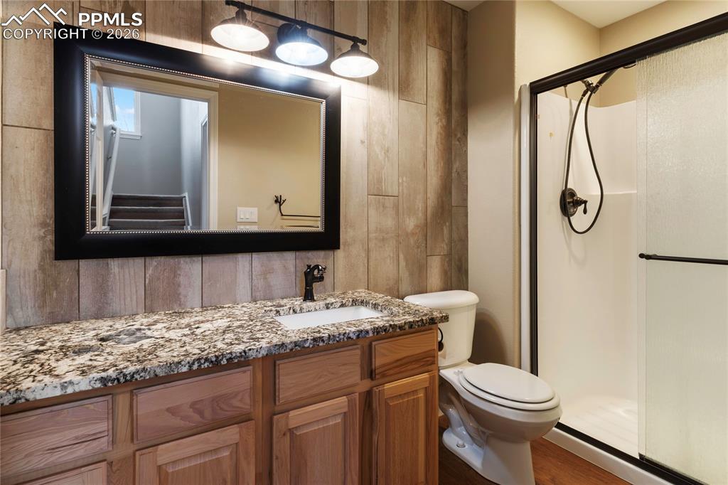 Image 14 of 29: Bathroom featuring a granite countertop vanity with wood cabinetry, a recta