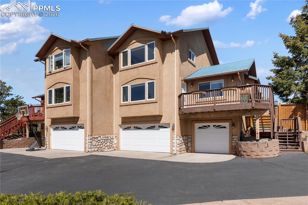 Image 2 of 29: Multi-level stucco exterior with three garage bays featuring arched window 