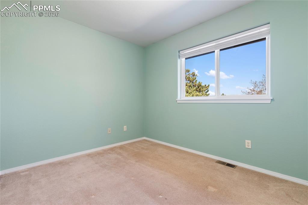 Image 21 of 29: Room with light green painted walls and neutral carpet flooring