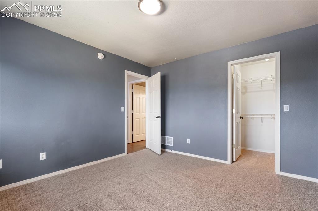 Image 22 of 29: Carpeted room with blue walls and white trim