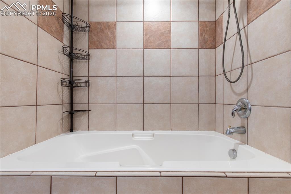 Image 25 of 29: Spacious built-in soaking tub featuring light-toned square wall tiles with 