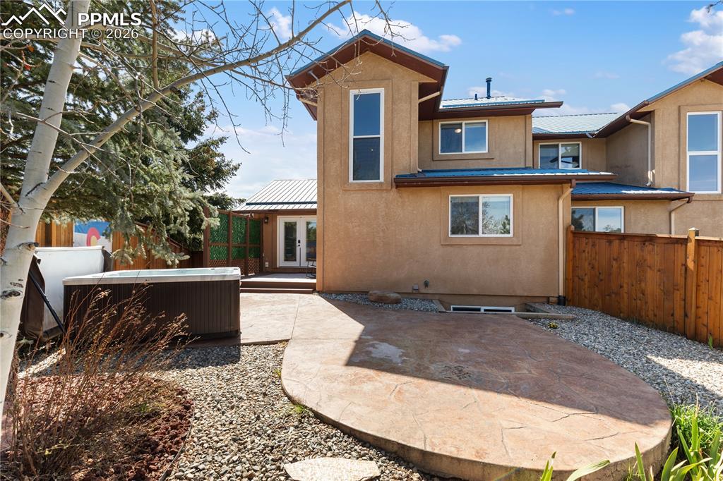 Image 27 of 29: Rear exterior featuring a patio with decorative concrete, a hot tub, and a 