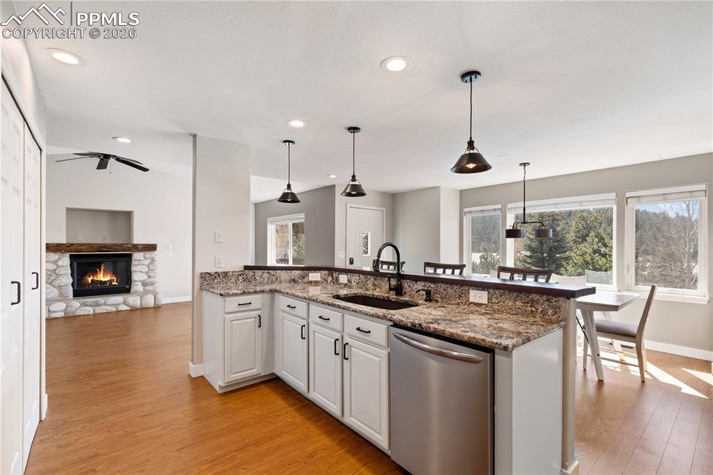 Image 3 of 29: Open-concept kitchen featuring granite countertops, white cabinetry, and st